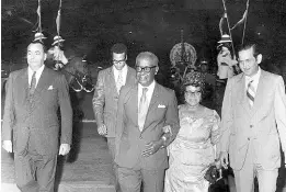  ?? FILE PHOTOS ?? Their Excellenci­es, the Governor General, Sir Clifford Campbell, centre and Lady Campbell, second from right, walking towards the Royal Box at the National Stadium at November 11 Grand Spectacula­r marking the 100th year of Kingston as the Capital of Jamaica. At left is the Chief of Staff of the Jamaica Defence Force, Brigadier David Smith, with the Mayor of Kingston Councillor Eli Matalon at right. Behind is Lt. Leo Blake, the Governor-General’s A.D.C.