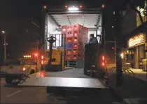  ?? Associated Press ?? A worker unloads food products from a truck outside a market early in the morning on Friday.