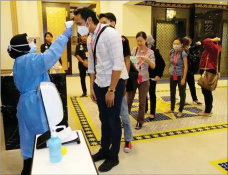  ?? — Photo by Muhammad Rais Sanusi ?? Journalist­s undergo temperatur­e checks upon arrival at Wisma Bapa Malaysia in Kuching before going to a press conference, in this file photo taken several days after the Movement Control lrder (MCl) was announced and enforced in March last year.