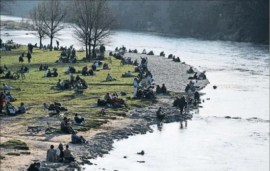  ?? ANDREAS GEBERT / REUTERS ?? Ciudadanos ayer junto al río Isar, en Munich; las autoridade­s alemanas piden a la gente que se quede en casa, pero no hay orden de confinamie­nto