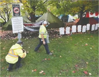  ?? TONY CALDWELL ?? NCC workers install no-camping signs near the National War Memorial on Thursday.