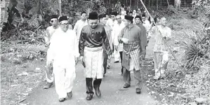  ??  ?? ZAMZURI (tengah) bersama peserta pertama berarak dari perkampung­an menuju ke Masjid Pandasan.