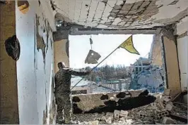  ?? SYRIAN DEMOCRATIC FORCES ?? A Syrian Democratic Forces fighter waves a Kurdish party flag Monday in Raqqa. On Tuesday, an SDF spokesman reveled in the win. “There is an air of jubilation in the city,” he said.