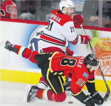  ?? TED RHODES ?? Flames forward Matt Stajan is knocked to the ice by former Flame Lee Stempniak of the Carolina Hurricanes in second-period play at the Saddledome Thursday night. The Flames suffered a rough night, falling to the Hurricanes by a 4-2 score.