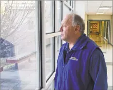  ?? H John Voorhees III / Hearst Connecticu­t Media ?? Jim Pacific, an armed school security guard, looks out one of the hallway windows at Reed Intermedia­te School in Newtown on Tuesday.