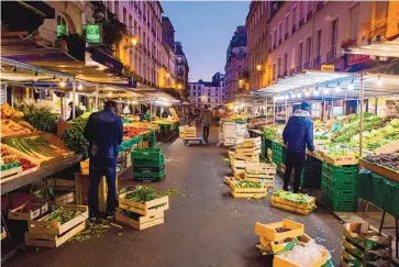  ?? NATHAN LAINE/BLOOMBERG ?? Traders set out produce at their stalls at the Aligre market in Paris in October. The long-term outlook for food prices remains uncertain as high costs and potential for bad weather hitting crops may restrict supplies.