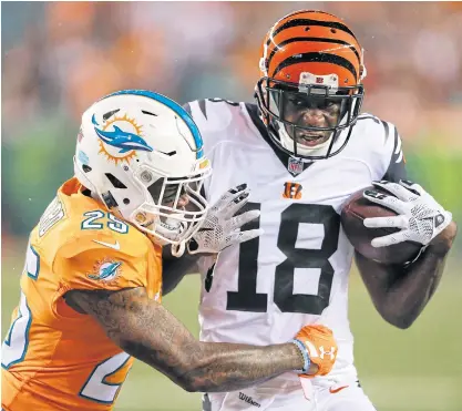  ??  ?? The Bengals’ AJ Green, right, runs the ball against the Dolphins’ Xavien Howard.