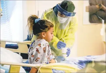  ?? Photograph­s by Irfan Khan Los Angeles Times ?? COVID-19 patient Rachel Ward, 6, is treated by nurse Jessica Serven at Rady Children’s Hospital last week in San Diego. Rachel, one of 28 coronaviru­s-positive children in the hospital that day, endured abdominal pain.