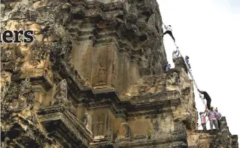  ??  ?? Gardeners preparing to climb up the tower of the Angkor Wat temple to remove tree saplings growing on it.