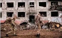  ?? Lynsey Addario/New York Times ?? Ukrainian soldiers walk by a destroyed building on Sunday in Druzhkivka, Ukraine, as fighting in Donetsk continues.