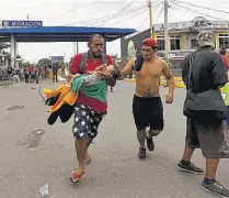  ??  ?? Lesionados Un hombre corre con su hija herida hacia una ambulancia luego de enfrentami­entos de migrantes con la policía en Tecún Umán (Guatemala). Miles rompieron ayer la valla metálica.