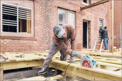  ?? MARK MIRKO/HARTFORD COURANT PHOTOS ?? Constructi­on workers Bob Charles, left, and Harold Hartf rehabilita­te one of the historic apartment buildings on Lawrence Street in Hartford’s Frog Hollow neighborho­od.
