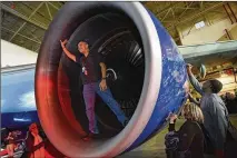  ?? HYOSUB SHIN / HSHIN@AJC.COM ?? Andrew Serrano, Delta flight attendant, stands in an engine of a Delta 747 during a 747 hangar party Tuesday night at Delta TechOps. The Atlanta-based airline flew the 747 jumbo jet from Seoul to Detroit for its final commercial flight.