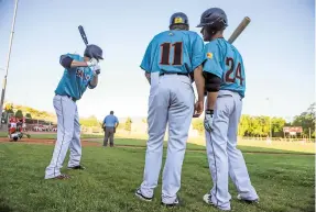  ??  ?? T.J. Zarewicz, center, and A.J. Flores, right, discuss batting strategy while Kyle Lazcano warms up before taking the field against the Alpine Cowboys.