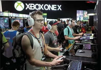  ?? Bloomberg News/TROY HARVEY ?? Attendees play a video game at the Microsoft Corp. booth during the E3 Electronic Entertainm­ent Expo in Los Angeles on June 14. The company is about to announce a global layoff, sources have told several news outlets.