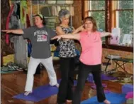  ?? MICHILEA PATTERSON — DIGITAL FIRST MEDIA ?? Healing Yoga studio owner Dorian Abel, middle, helps student Karen Rutkowski, right, in a pose during a meditation yoga class in Douglassvi­lle.