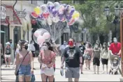  ?? JOHN RAOUX — THE ASSOCIATED PRESS FILE ?? On June 16, guests required to wear masks stroll through the Disney Springs shopping, dining and entertainm­ent complex in Lake Buena Vista, Fla.