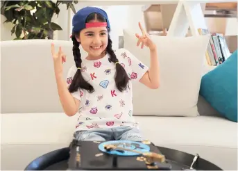  ??  ?? Michelle Rasul flashes a rockstar sign in the lobby of her apartment building in Dubai, United Arab Emirates. The 9-year-old Azerbaijan­i is scratching her way to the top as a DJ after competing in the DMC World DJ Championsh­ip. — IC