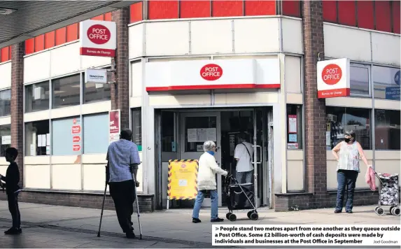  ?? Joel Goodman ?? People stand two metres apart from one another as they queue outside a Post Office. Some £2 billion-worth of cash deposits were made by individual­s and businesses at the Post Office in September