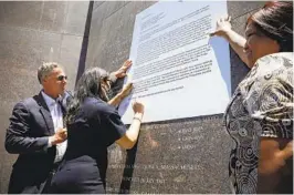  ?? NANCEE E. LEWIS FOR THE U-T ?? Reps. Scott Peters and Sara Jacobs sign their names to an enlarged letter, held by JoAnn Fields, urging the naming of a U.S. Navy ship in honor of Telesforo Trinidad at the USS San Diego Memorial on Harbor Drive in May 2021.