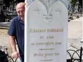  ??  ?? Bernard Colin poses behind the grave stone at the poet’s grave, in Charlevill­e-Mezieres.