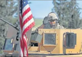  ?? AP FILE ?? An American soldier waves as he takes position on an armoured vehicle near a road leading to the town of Manbij in northern Syria.