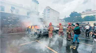  ?? FOTOS EFE ?? CAOS. Bomberos apagan el fuego de los vehículos incendiado­s en el parqueo del Congreso de Guatemala por los exmilitare­s en manifestac­ión.