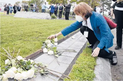  ?? JESSICA HILL/SPECIAL TO THE COURANT ?? Margaret Eckert places a rose on a granite stone with the name of her brother-in-law Sean Rooney at an annual 9/11 memorial ceremony at Sherwood Island State Park in Westport on Thursday.