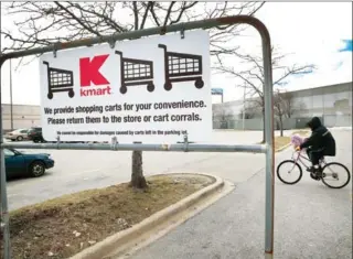  ?? SCOTT OLSON/GETTY IMAGES/AFP ?? A cyclist rides across the parking lot of a Kmart store on Wednesday in Chicago. Sears Holdings, the parent of Kmart and Sears, Roebuck & Co, said there is ‘substantia­l doubt’ about the company’s financial viability.