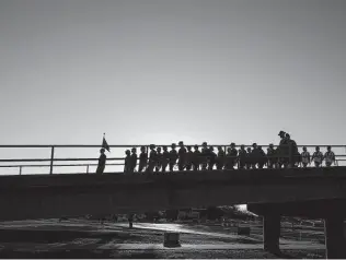  ??  ?? Airmen make their way across a bridge to their graduation ceremony at JBSA-Lackland. Because of the pandemic, recruits’ family members aren’t allowed to attend the ceremony.