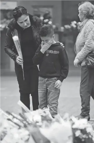  ?? JEFF J. MITCHELL/GETTY IMAGES ?? People pause to look at tributes in St. Ann’s Square in Manchester, England, to victims of the explosion at Manchester Arena on Monday. Rather than giving in to the fear inspired by terrorism, parents need to help their kids triumph over the darkness,...