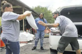  ??  ?? New homeowner Breanna Landers, 30, of Brandon, thanks park rangers Elizabeth Peterson and Chad Cash while they load sandbags inside the trunk of her vehicle at a Hillsborou­gh County site to help residents prepare for Tropical Storm Elsa, at Edward Medard Conservati­on Park in Plant City, Florida.