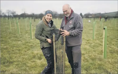  ??  ?? GREEN FINGERS: Joan Childs, head of volunteeri­ng for the National Park Authority, and Alasdair Fagan, woodland creation officer, join the tree-planting operation.