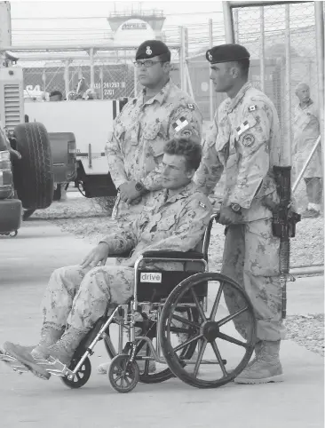  ?? TOBI COHEN / THE CANADIAN PRESS ?? Glen Kirkland, in wheelchair, injured in a direct fire explosion Sept 4, 2008, attends the ramp ceremony for fallen comrades Cpl. Andrew Grenon, Cpl. Mike Seggie and Pvt. Chad Horn in Kandahar.