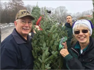 ?? PAUL POST — DIGITAL FIRST MEDIA ?? Vietnam veteran Robert Van Pelt, left, helps Ellms Family Farm co-owner Sally Ellms move one of the 130 trees donated by area growers.