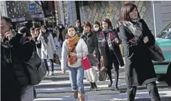  ?? — AFP ?? TOKYO: People cross an intersecti­on in the Ginza shopping district.