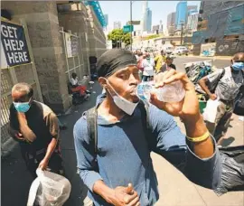  ?? Al Seib For The Times ?? RIEYELY MILLER, 19, drinks water he received from downtown Los Angeles’ Midnight Mission, which is “seeing more heat-related illnesses on skid row.”