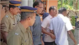  ?? — AFP ?? KOCHIN: In this photograph, Indian police officials escort priest Robin Vadakkumch­ery, center, after his arrest in Peravoor, some 300kms north of Kochin in the southern Indian state of Kerala.