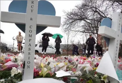  ?? Scott Olson/Getty Images ?? Flowers and crosses are set at the base of “The Rock” statue Wednesday on the campus of Michigan State University as a tribute to the students killed and wounded in Monday’s shooting.