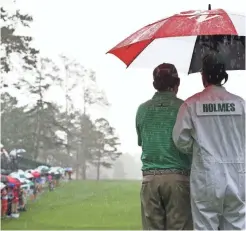  ??  ?? J.B. Holmes and his caddie share an umbrella as rain falls at the 14th tee in Monday’s practice round.