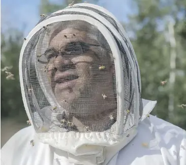  ??  ?? Carlos Castillo, applied science manager at the National Bee Diagnostic Centre near Grande Prairie, collects research samples from Craig Toth’s bee hives near Morinville on Aug. 11.