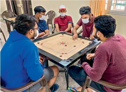  ?? PTI ?? In this handout photo provided by Indo-Tibetan Border Police, Indian nationals who were airlifted from coronaviru­s-hit Hubei province of Chinas Wuhan, play carrom inside a quarantine facility set by up ITBP at Chhawla area of New Delhi on Sunday. —