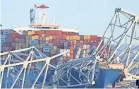  ?? AFP VIA GETTY IMAGES ?? The frame of the Francis Scott Key Bridge sits on top of a container ship after the bridge collapsed.