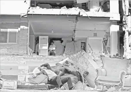  ?? Atta Kenare AFP/Getty Images ?? A MAN catches a break amid salvaged belongings outside damaged buildings in Sarpol-e Zahab, Iran. The magnitude 7.3 quake that struck near the border with Iraq on Sunday has left more than 500 people dead and thousands hurt in Iran. Iraq also suffered...