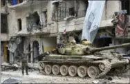  ?? THE ASSOCIATED PRESS ?? Syrian army soldiers flash the victory sign near their tank in the Sukkari neighborho­od of east Aleppo, Syria, on Friday.