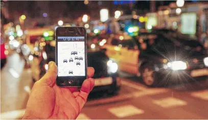  ?? QUIQUE GARCIA/AFP/GETTY IMAGES ?? The Uber app is seen on a smartphone as cabs pass. Finding a fair solution to the Uber problem is possible, writes Don Cayo.