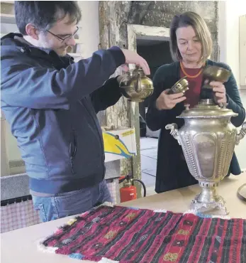  ?? FOTO: KATRIN NEEF ?? Maximilian Eiden und Andrea Maria Schreck bauen einen Samowar zusammen, mit dem Tee zubereitet wird. Ein ehemaliger Gastarbeit­er aus der Türkei hat ihn als Ausstellun­gsstück zur Verfügung gestellt.