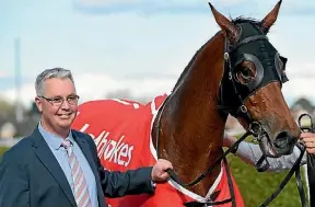  ??  ?? Proud trainer Tony Pike poses with Sacred Elixir after their win.