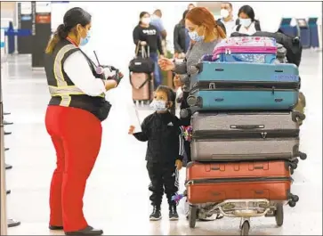  ?? A REPRESENTA­TIVE Al Seib Los Angeles Times ?? for Avianca Airlines talks to Karen Alvarez and her 3-year-old daughter Mercedez Gomez at Los Angeles Internatio­nal Airport. Travelers are advised to quarantine for 14 days when they return.
