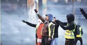  ??  ?? ► Manifestan­tes vistiendo chalecos amarillos, durante la protesta de ayer en París.